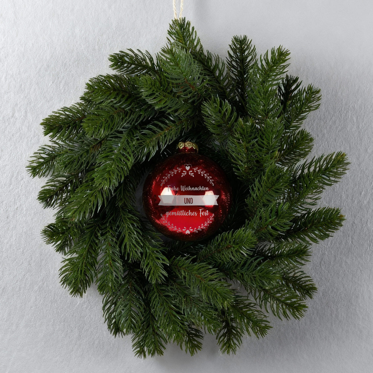 Türkranz an grauer Wand mit roter gravierter Weihnachtskugel