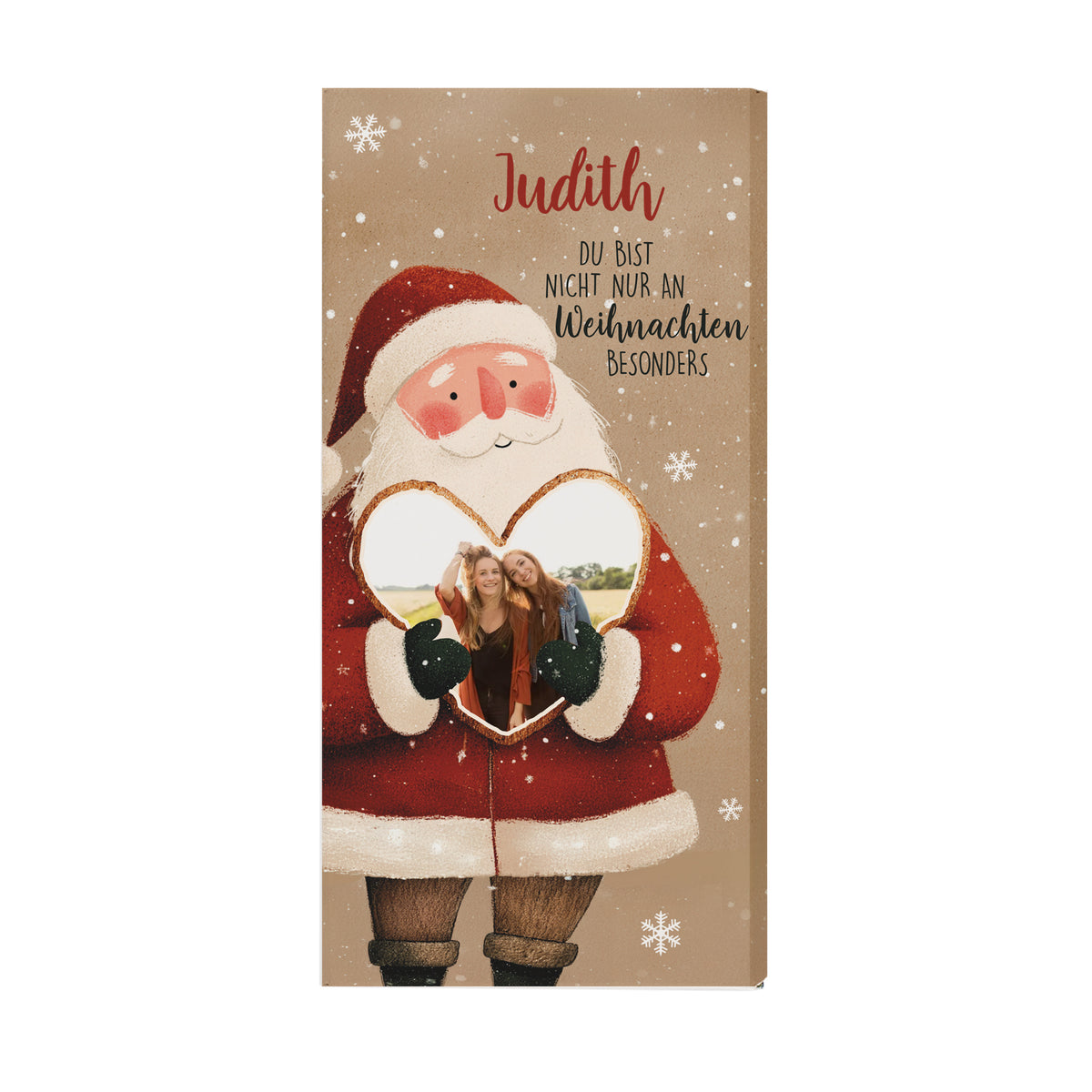 Weihnachts-Schokolade mit Herzfoto und Namensdruck. Die Verpackung zeigt einen Weihnachtsmann mit rotem Mantel, weißen Schneeflocken und dem Namen „Judith“. Das Foto ist in das Herz integriert. Die naturbraune Farbgebung der Verpackung sorgt für einen modernen und warmen Look – perfekte Geschenkidee für die Feiertage.