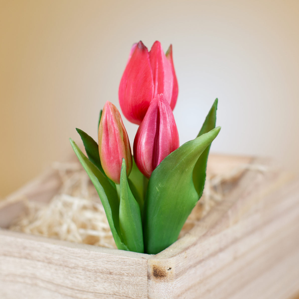 Kunstblumenstrauß aus drei rosa Tulpen in Pflanzkorb aufgestellt