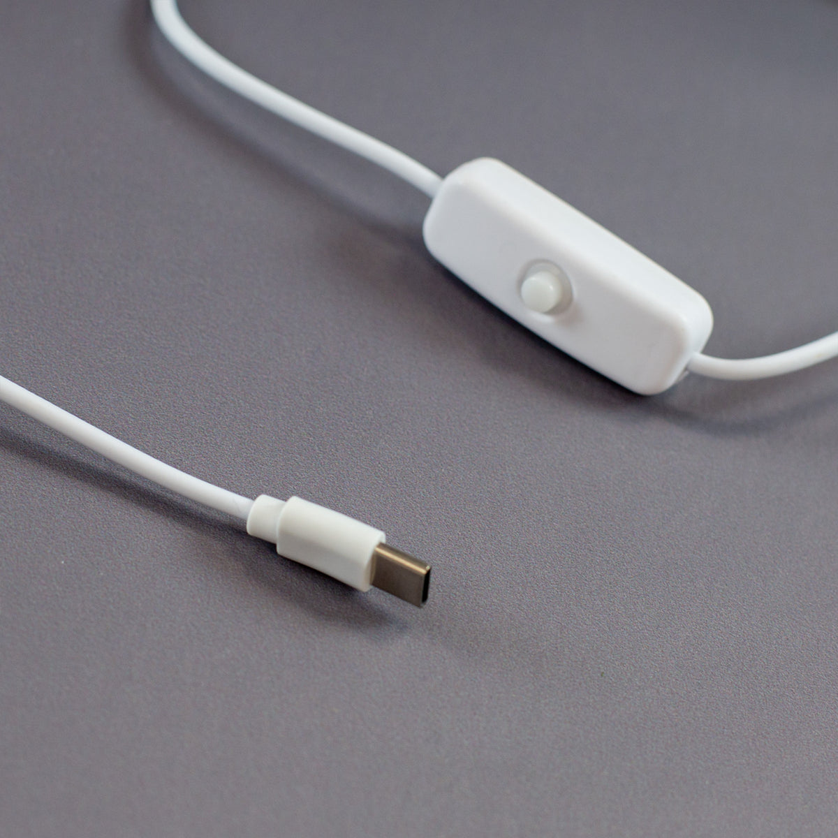 USB-C Kabel der LED Acryl-Lampe mit weißem An/Aus-Schalter und Stecker in Nahaufnahme auf grauem Hintergrund