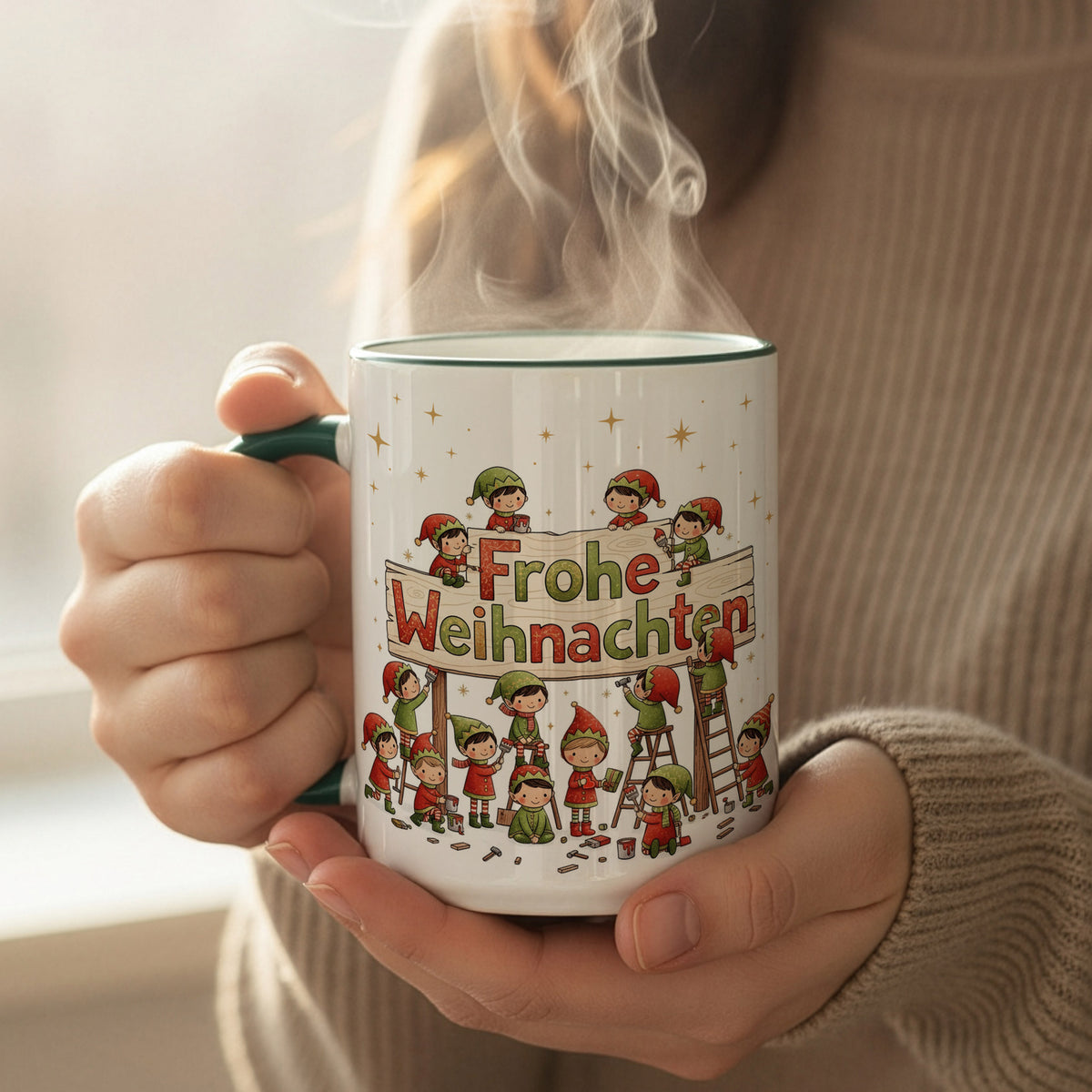Person hält eine dampfende Weihnachtstasse mit werkelnden Wichteln am „Frohe Weihnachten“-Schild vor einem hellen Fenster.