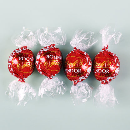 Vier Lindt Lindor Kugeln in roter Verpackung aus Vollmilch-Schokolade