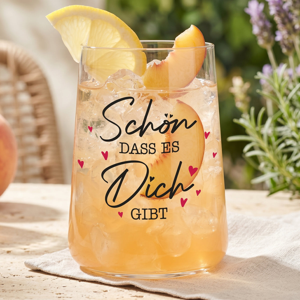 Trinkglas mit Pfirsichgetränk, Eiswürfeln, Zitrone und liebevollem Herz-Aufdruck