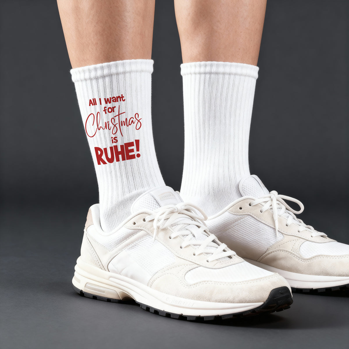 Weiße Tennissocken mit rotem Weihnachtsaufdruck ‚All I want for Christmas is RUHE!‘, getragen in weißen Sneakern.