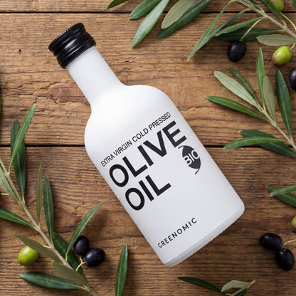 Weißes BIO Olivenöl in Designerflasche auf Holztisch mit Olivenzweigen
