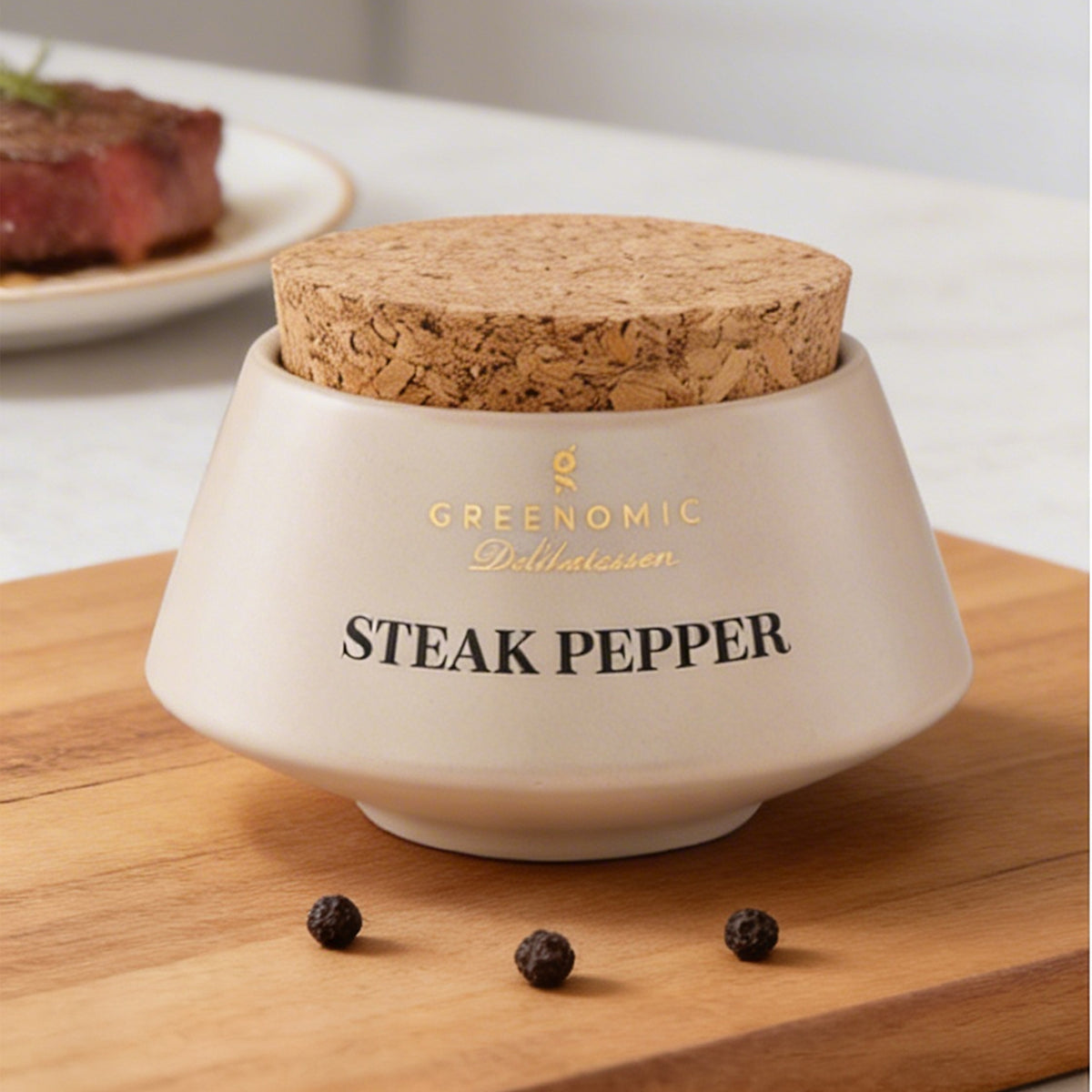 Steak Pepper Gewürz im Keramikbehälter auf Holzbrett mit Steak im Hintergrund