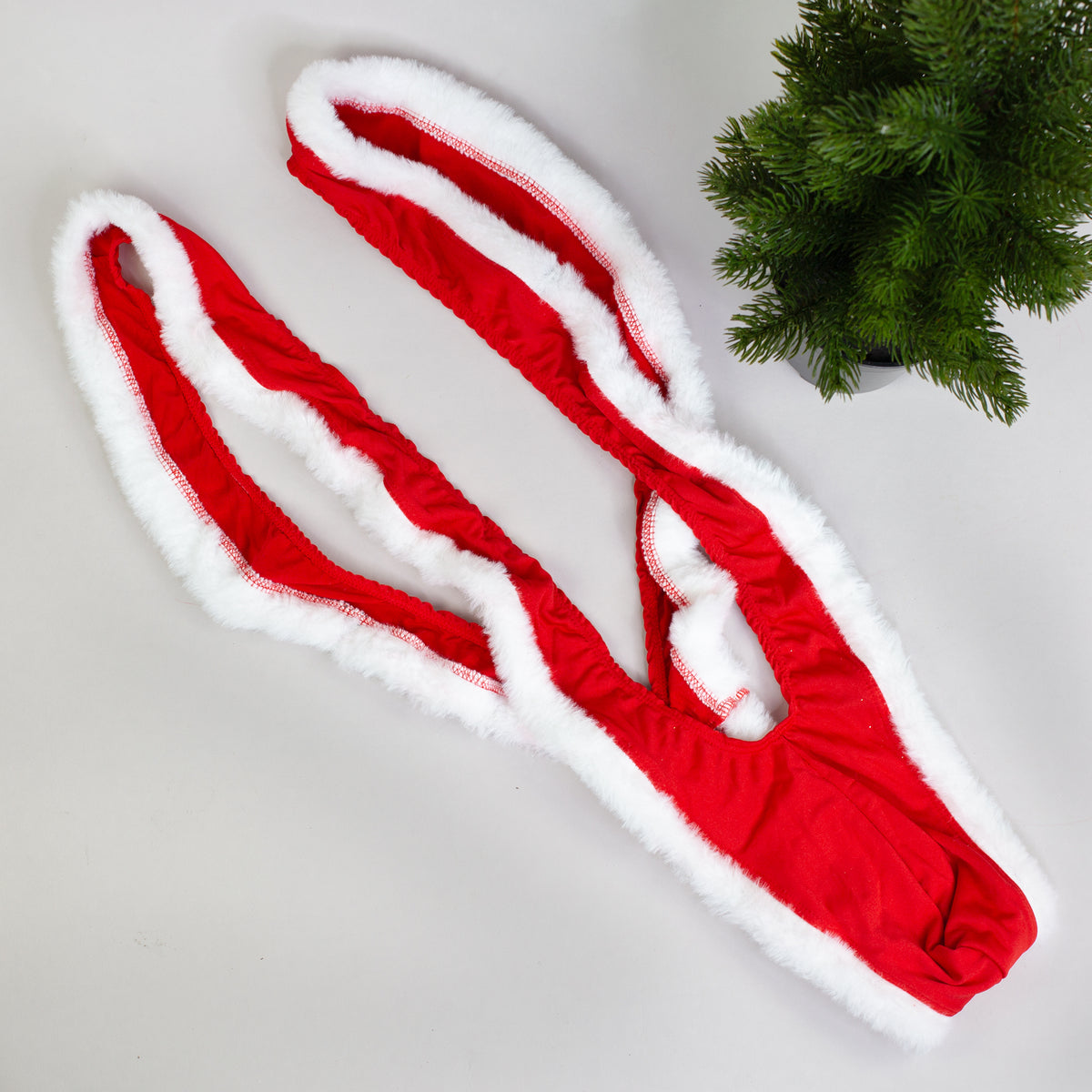 Weihnachts-Mankini Variante mit durchgehend weißem Kunstpelzrand, flach auf Hintergrund.