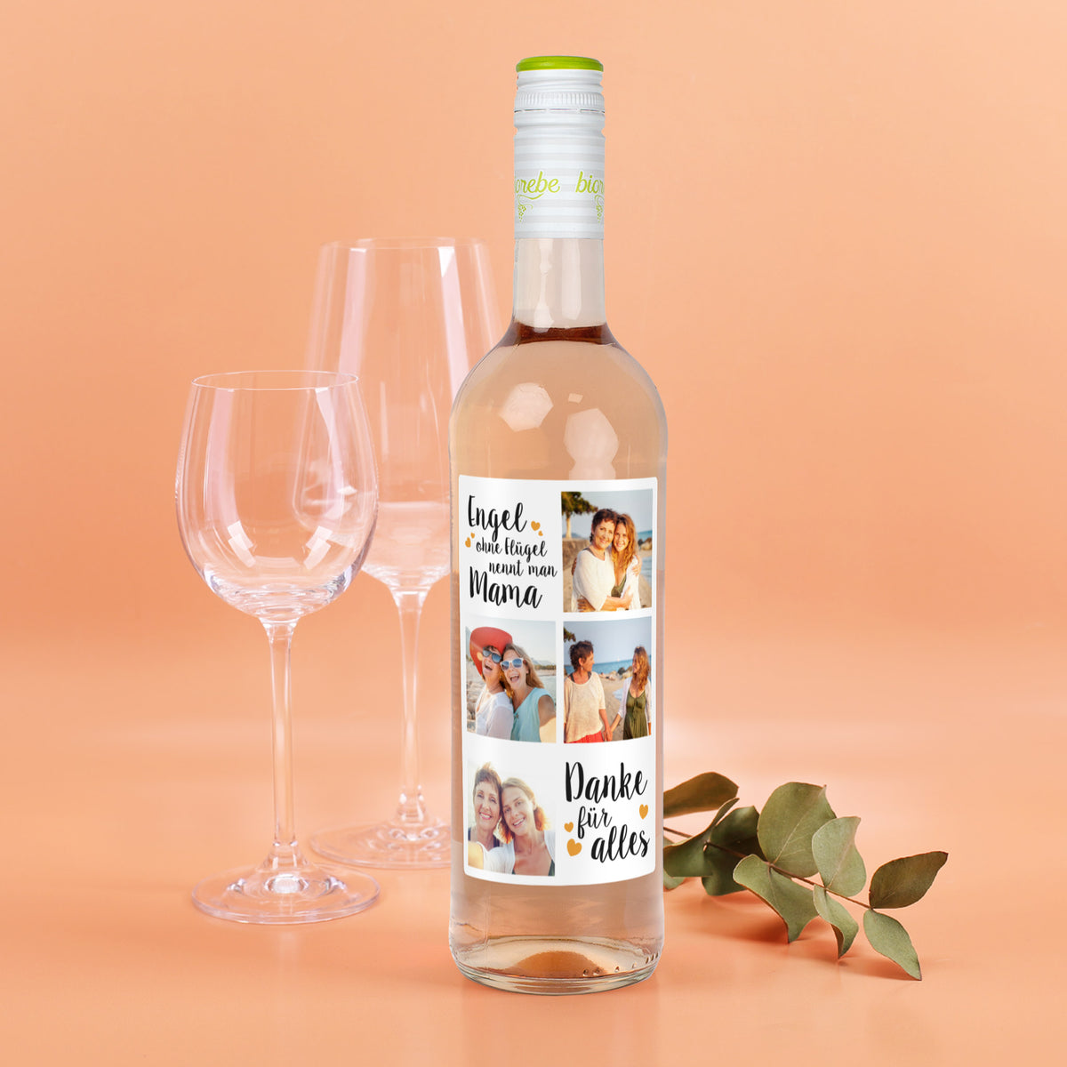 Flasche Roséwein mit personalisiertem Etikett „Engel ohne Flügel nennt man Mama – Danke für alles“, vier Fotos und Dekoration, vor hellem Hintergrund mit Gläsern.