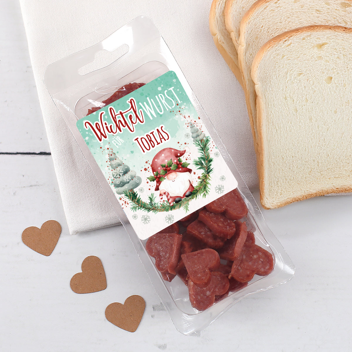Personalisierte Wichtel-Wurst mit Name auf weihnachtlichem Etikett und herzförmiger Mini-Salami.