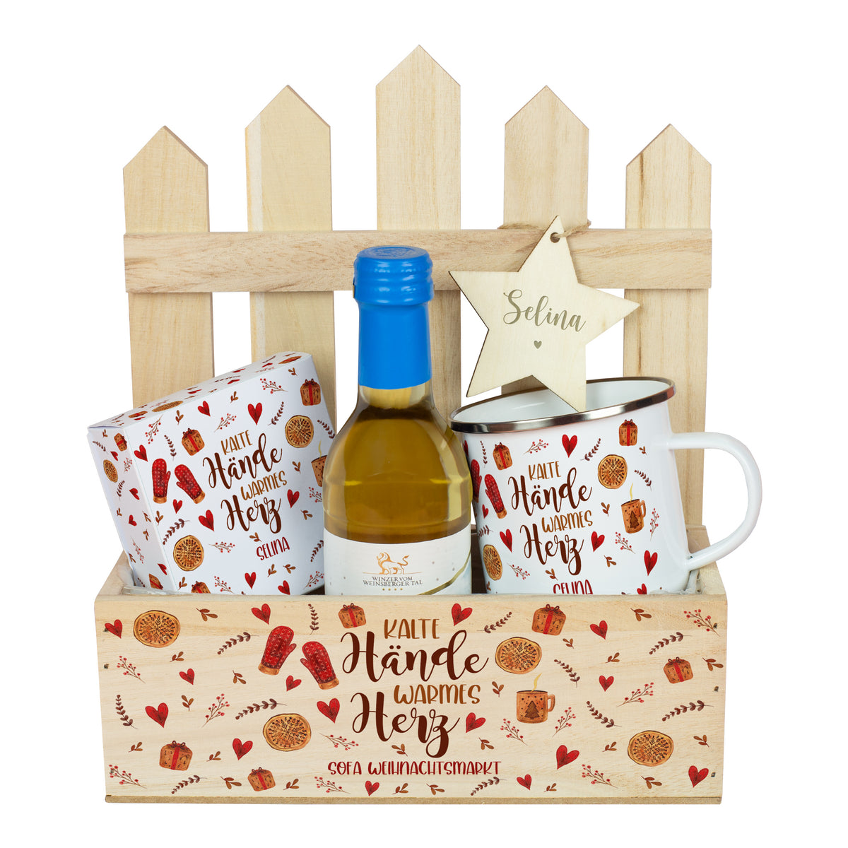 Personalisierter Weihnachtsmarkt-to-Go Korb aus Holz mit kleinem Winzerglühwein in Weiß, individualisierter Metalltasse und Lindor-Geschenkbox. Am Zaunelement hängt ein gravierter Stern mit Namen, dekoriert mit natürlichen Tannenzweigen.