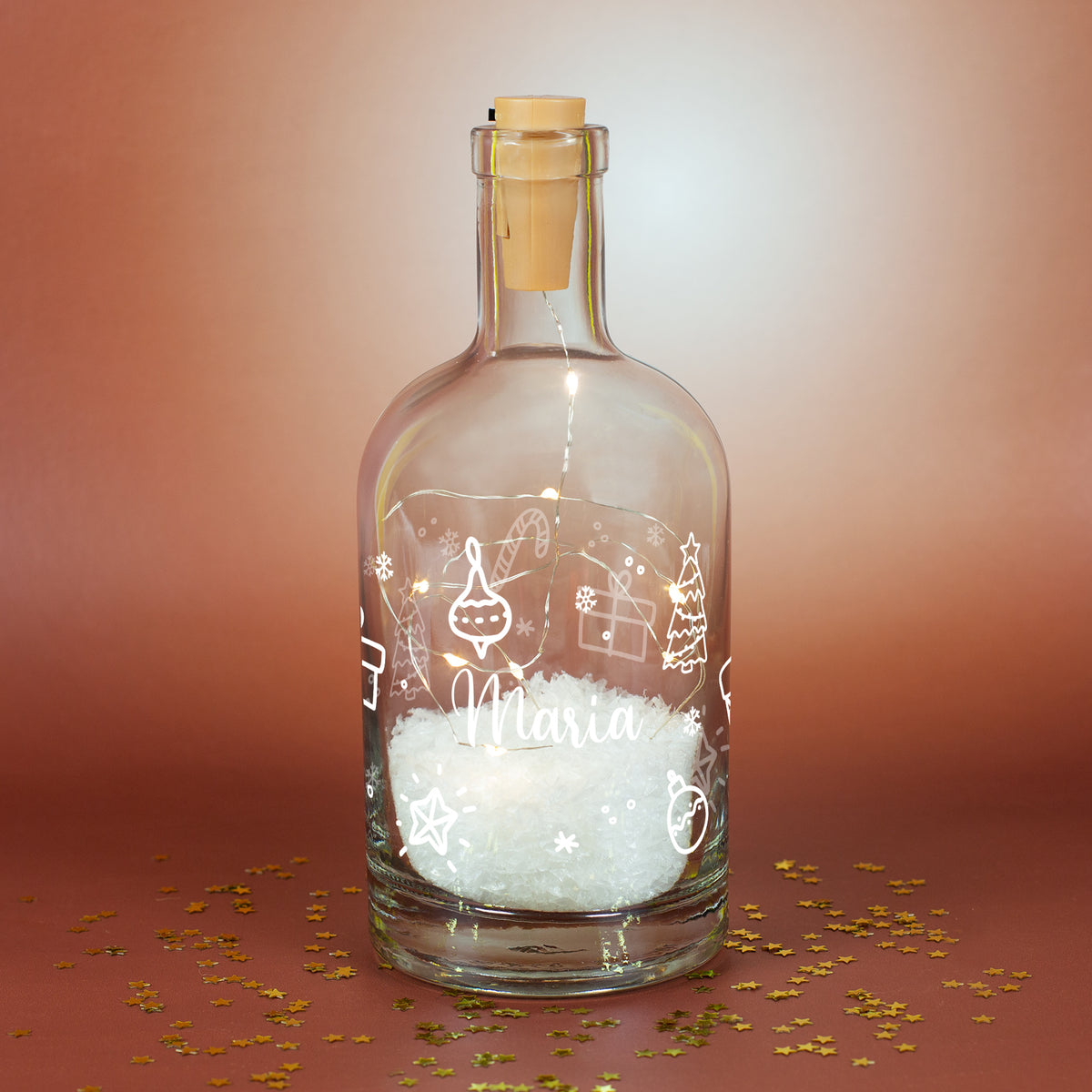 Personalisierte LED-Deko-Karaffe mit weißem Weihnachtsornament-Motiv, Kunstschnee und warmweißer Lichterkette, Name „Maria“ auf braunem Hintergrund.