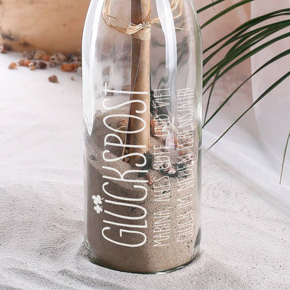Flaschenpost mit Sand, Muscheln und marmoriertem Papier