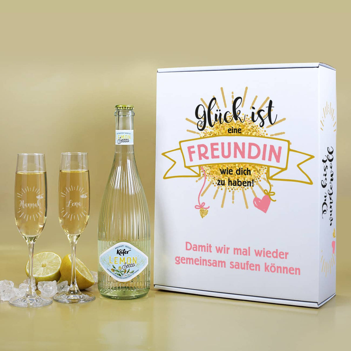 Geschenkset bestehend aus Papp-Geschenkverpackung  bedruckt mit einem niedlichen Motiv, Sektgläsern im 2er-Set mit persönlicher Gravur und eine Fruchtsecco mit Lemon Geschmack