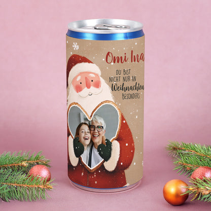 Personalisierte Secco-Dose mit Weihnachtsmann hält goldenes Herz mit Foto von Oma und Enkel, Name „Omi Ina“ aufgedruckt.