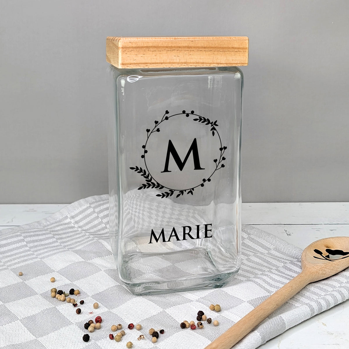 Glasvorratsbehälter mit Initiale „M“ und Name „MARIE“, auf Tisch mit Geschirrtuch, Variante in Schwarz