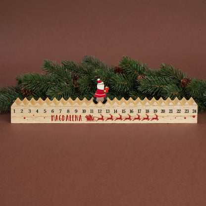 Personalisierter Walking-Santa-Weihnachtskalender „Magdalena“ aus Holz vor Tannenzweigen und weihnachtlicher Dekoration