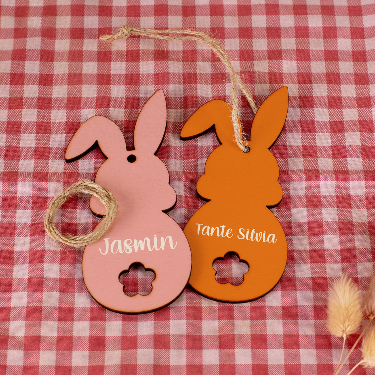 Zwei Holzanhänger in Hasenform in Rosa und Orange, bedruckt mit Namen
