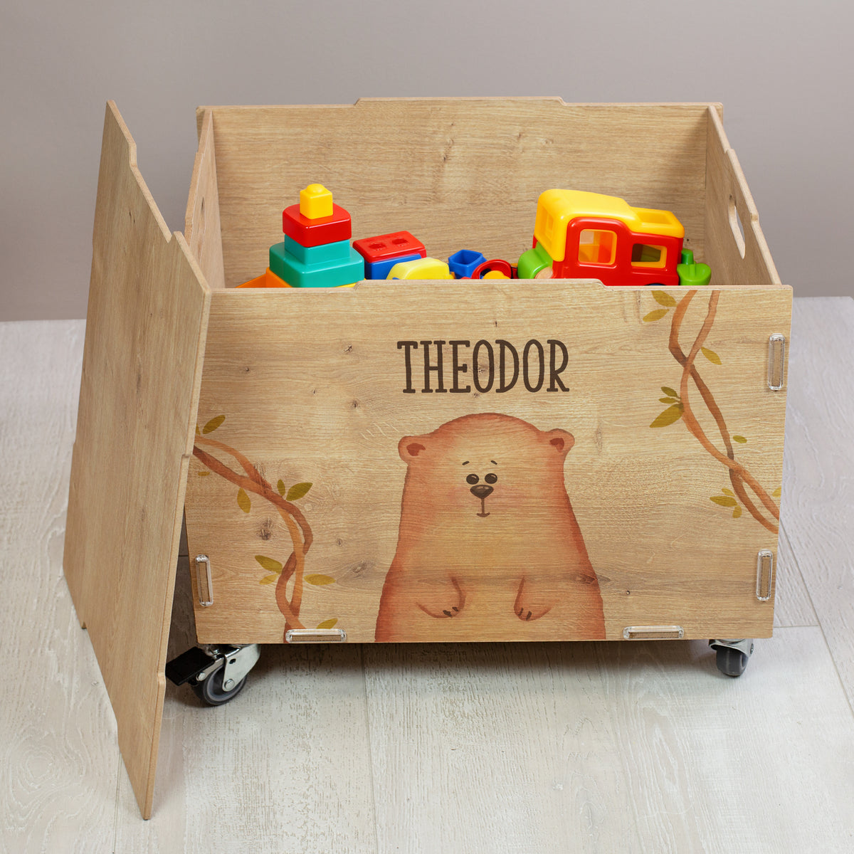 Offene Rollbox aus Holz mit Bären-Motiv und personalisiertem Namen „Theodor“, befüllt mit Spielzeug, seitlich aufgeklappter Front