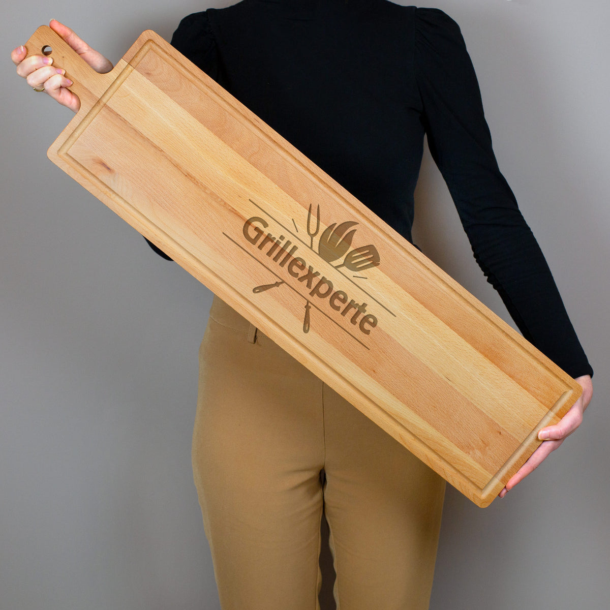 Person hält langes Servierbrett aus Buchenholz mit Grillmotiv und personalisierter Gravur