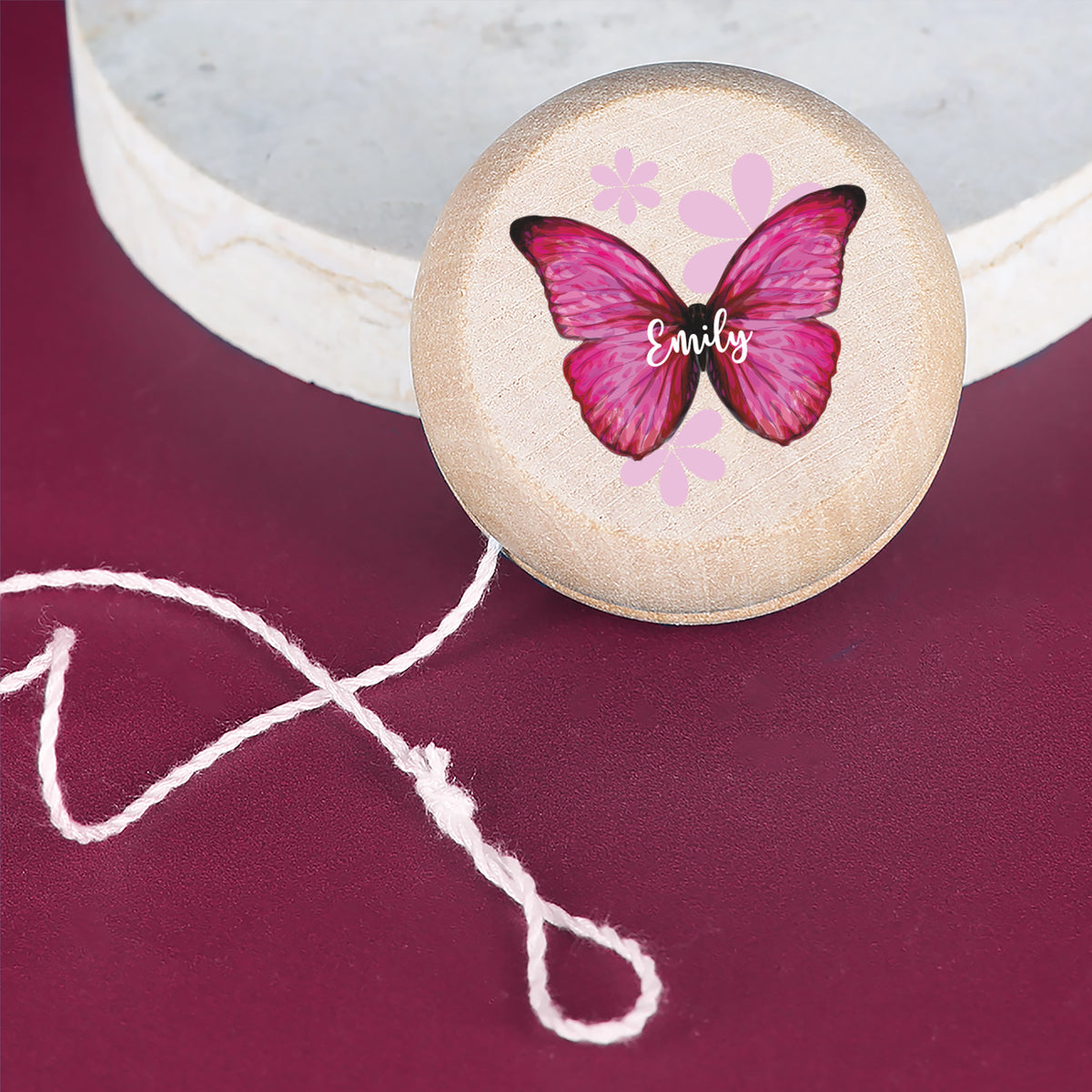 Yo-Yo aus Holz mit pinkem Schmetterling und Name Emily auf dunklem Hintergrund