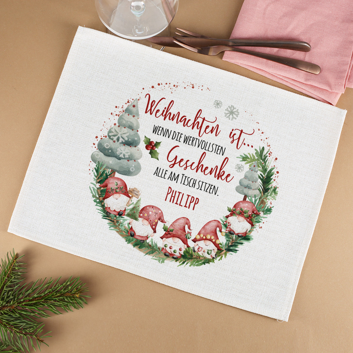 Weihnachtliches Platzdeckchen mit Spruch „Weihnachten ist, wenn die wertvollsten Geschenke alle am Tisch sitzen“, personalisiert mit Namen Philipp, auf Tisch mit Glas und Besteck.
