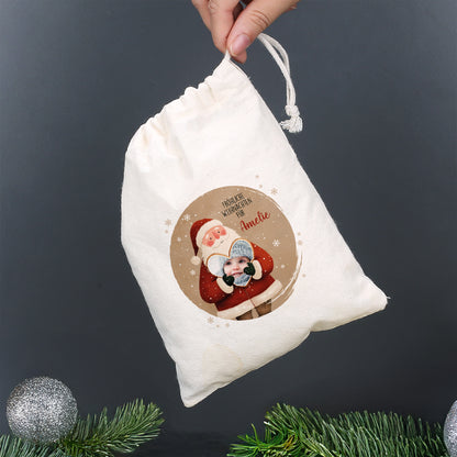 Kleiner Geschenksack mit Weihnachtsmann und Foto im Herz, Text „Fröhliche Weihnachten für Amelie“, in Hand gehalten – nachhaltige Geschenkverpackung zu Weihnachten.