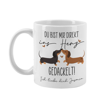 Freigestellte Produktansicht: Personalisierte Dackel-Tasse mit Spruch „Du bist mir direkt ins Herz gedackelt!“ und Wunschtext auf weißem Hintergrund