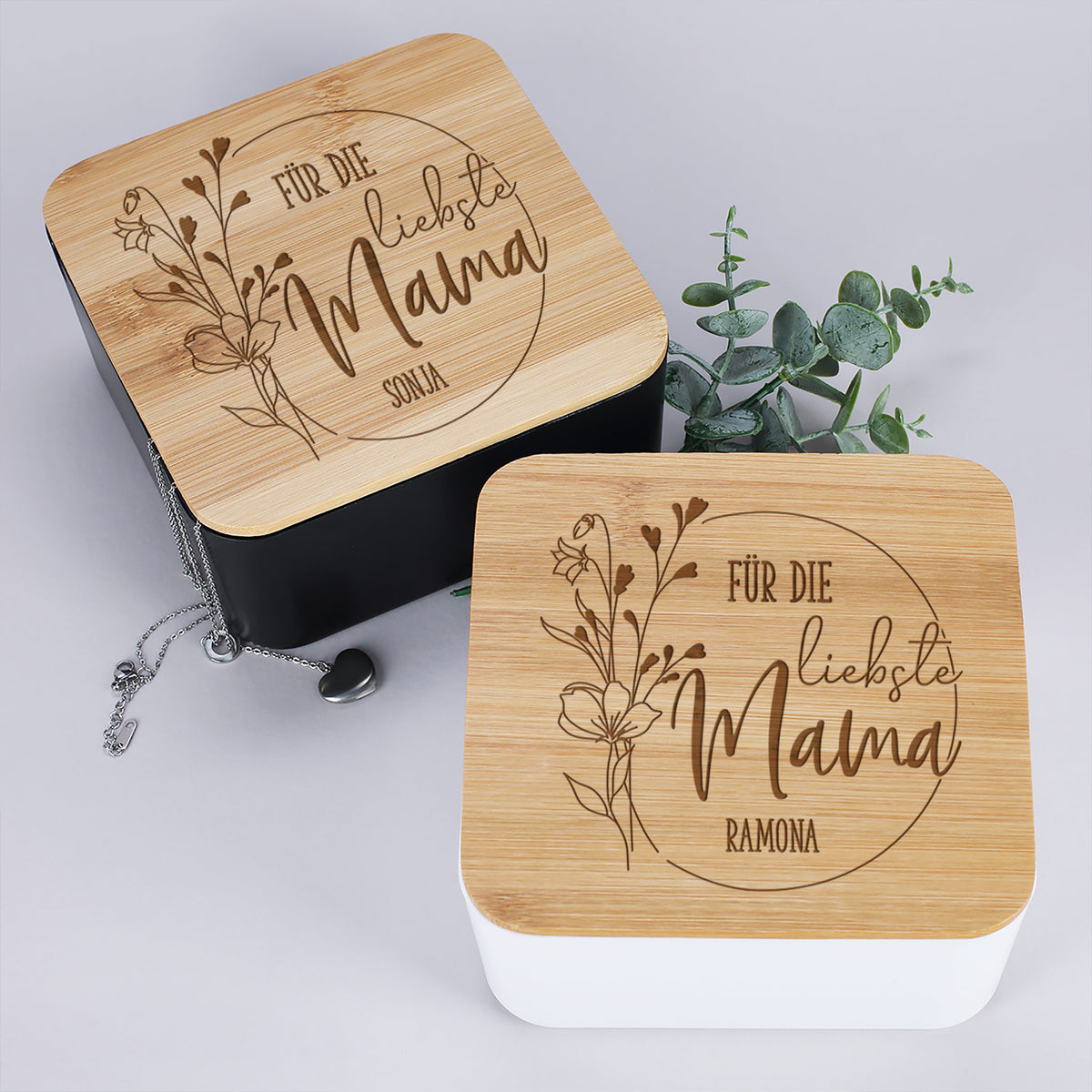 Weiße und schwarze Variante des personalisierten Schmuckkastens mit Bambusdeckel nebeneinander stehend – beide mit Gravur „Für die liebste Mama“ und individuellem Namen.