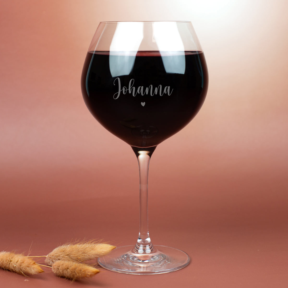 Leonardo Burgunderglas mit Gravur „Johanna“ und Herzsymbol, gefüllt mit Rotwein – elegantes Weinglas mit gezogenen Stiel vor warmem Hintergrund, ideal als personalisiertes Geschenk.
