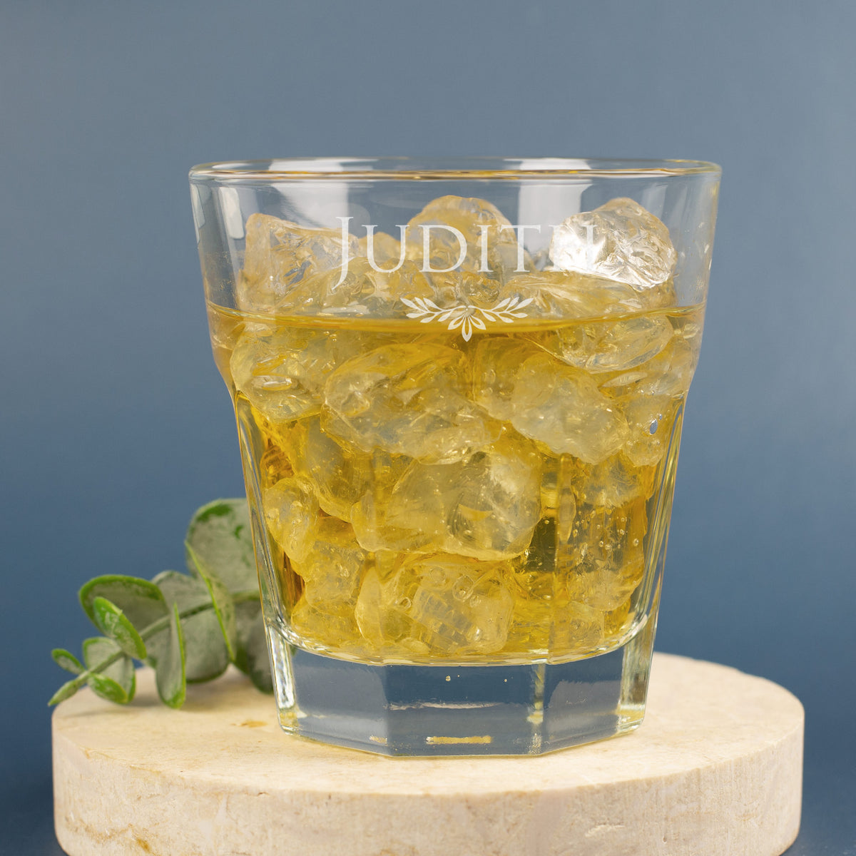 Personalisiertes Glas mit Gravur von Name und Ranke, dekoriert mit Eukalyptus, auf hellem Untergrund