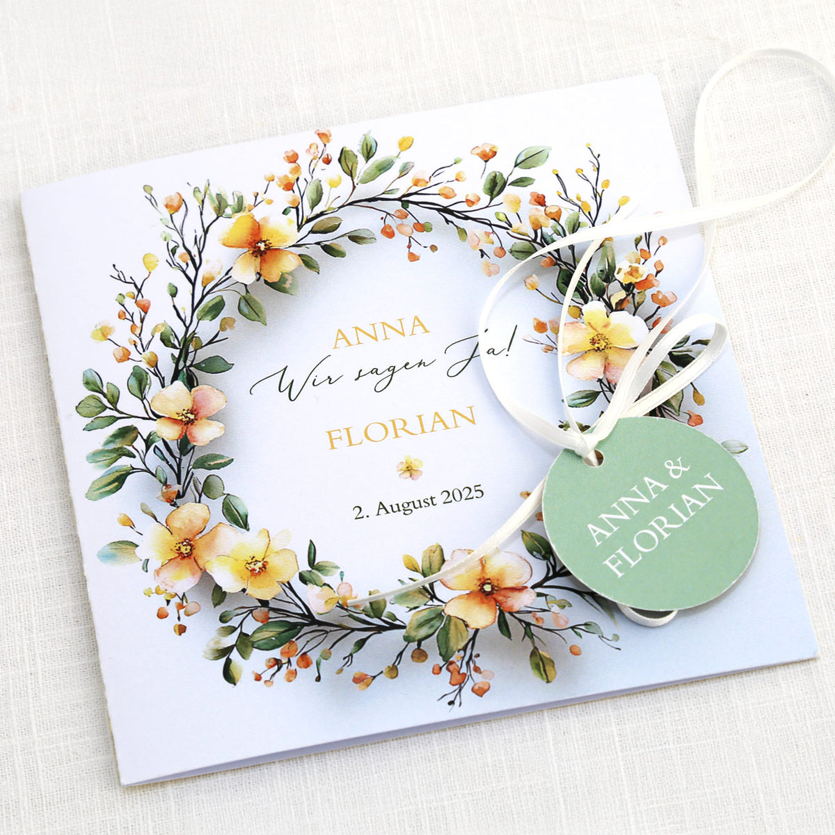 Einladungskarte zur Hochzeit mit Blütenkranz und rundem Anhänger