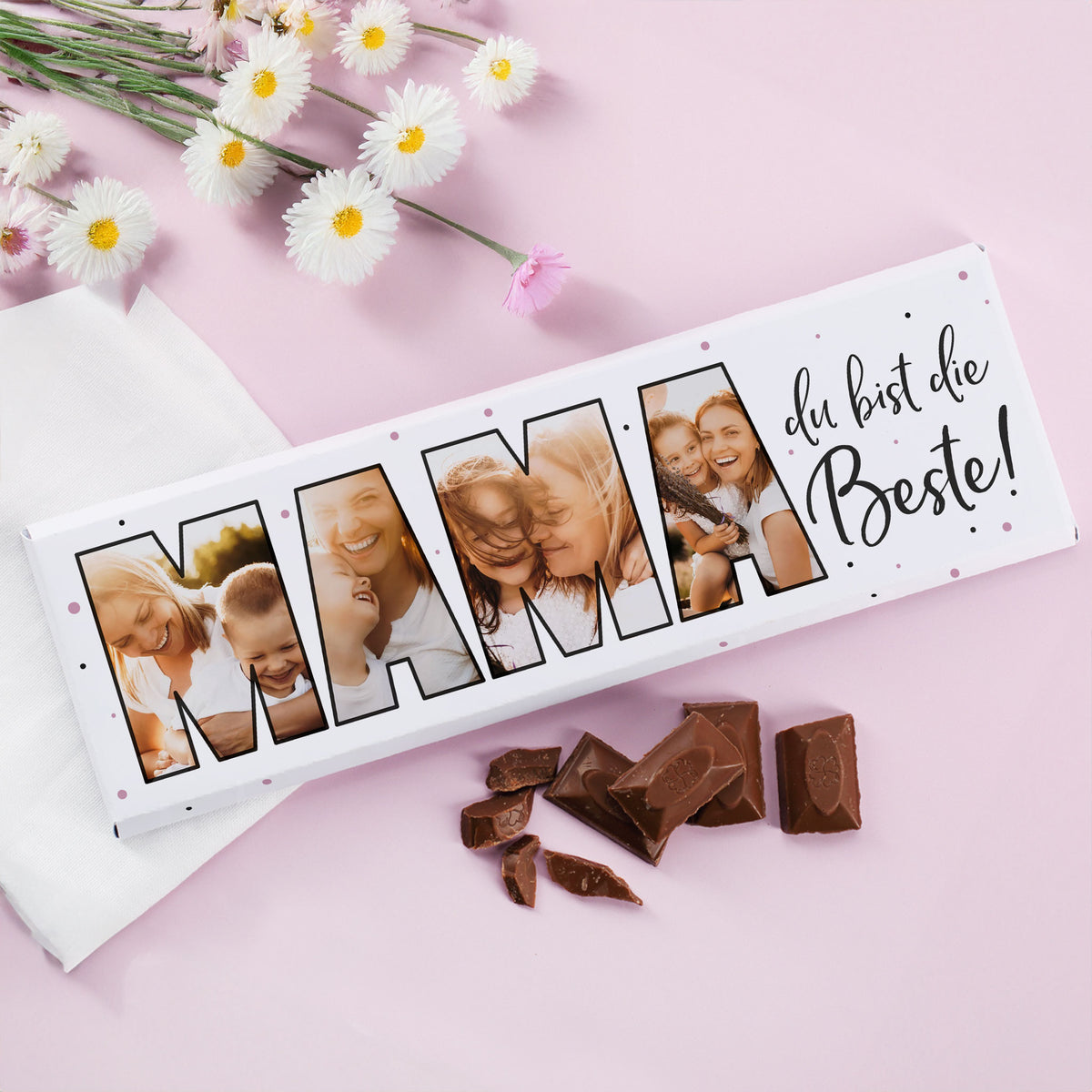 XXL Schokoladentafel „Mama du bist die Beste!“ mit 4 personalisierten Fotos und Schokoladenstücken daneben auf rosa Hintergrund mit Blumen