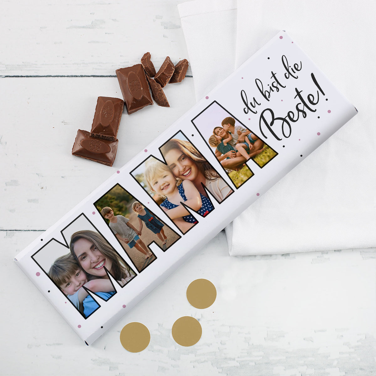Personalisierbare Fotogeschenk-Schokolade für Mama mit 4 Bildern im Schriftzug „MAMA“ und aufgebrochener Schokolade auf weißem Tisch