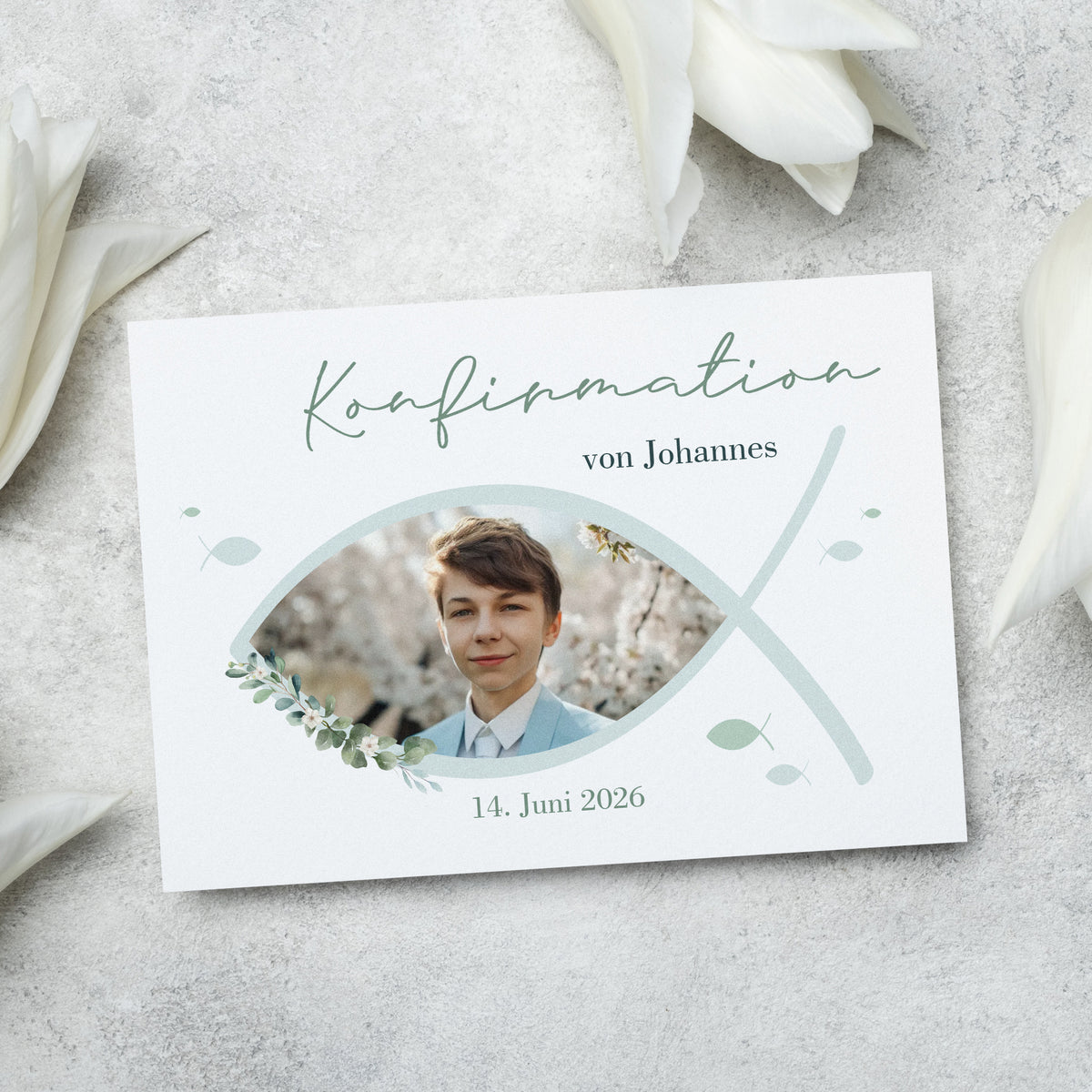 Einladungskarte zur Konfirmation mit christlichem Ichthys-Fischsymbol. Vorderseite mit personalisiertem Foto, zarten Blätterelementen und sanften Grüntönen. Hochwertiger Druck auf edlem Feinstpapier.