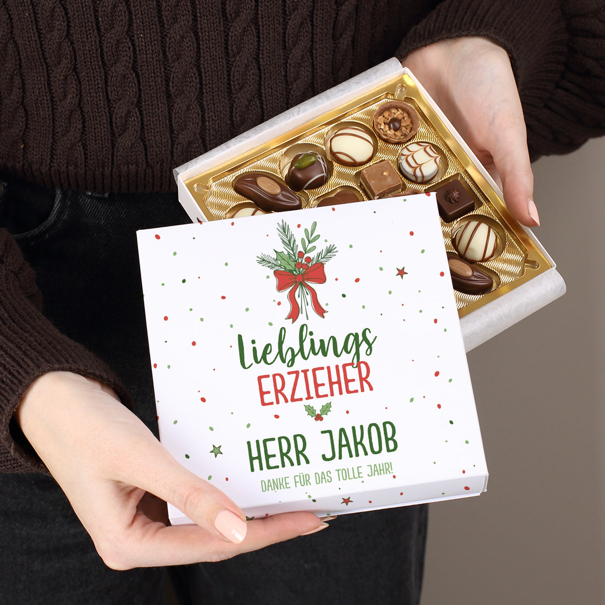 Lindt Pralinenbox mit Weihnachtsmotiv „Lieblingsmensch“, geöffnet in der Hand, individuell bedruckt mit Wunschtext.