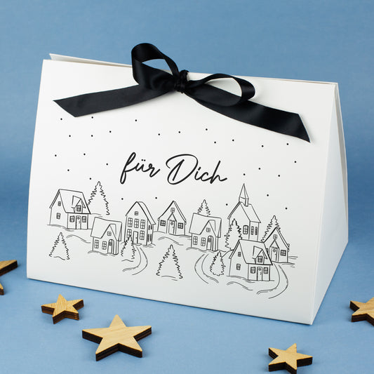 Sehr große Geschenktasche mit Winterdorf-Motiv und personalisiertem Text „für Dich“, auf blauem Hintergrund mit Holzsternen arrangiert.