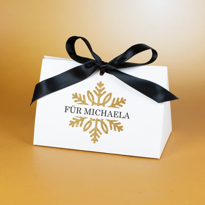 Mittlere Geschenktasche mit goldener Schneeflocke und personalisiertem Text „Für Michaela“, dekorativ vor goldenem Hintergrund gezeigt.