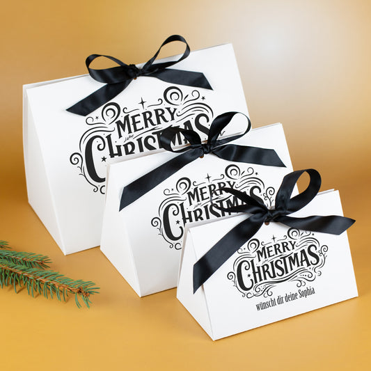 Drei Größen der personalisierten „Merry Christmas“-Geschenktasche mit schwarzen Satinschleifen im Größenvergleich