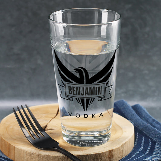 Trinkglas mit schwarzem Adler-Motiv und Schriftzug „Vodka“, personalisiert mit Name Benjamin, gefüllt mit Wasser auf Holzbrett