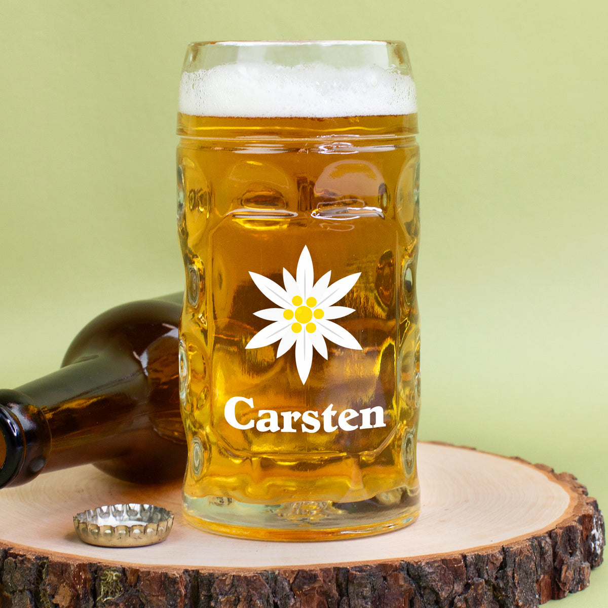 Bierglas mit Edelweiß-Print und Name Carsten auf Holzunterlage – daneben Flasche und Kronkorken