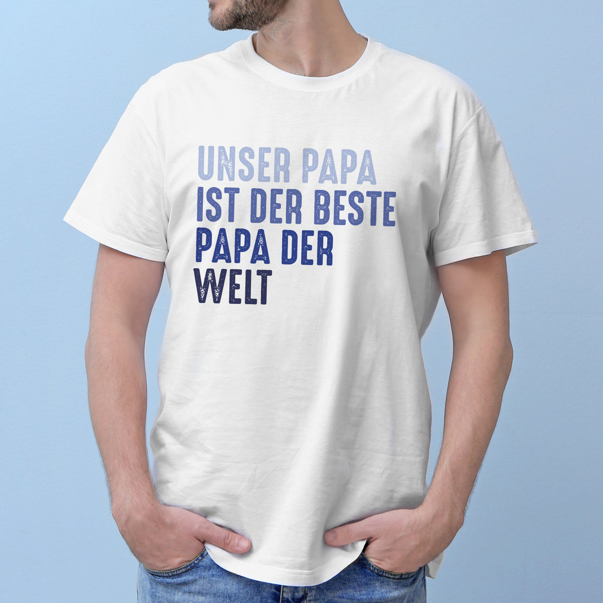 Mann mit weißem T-Shirt vor blauer Wand, Text: „Unser Papa – ist der beste – Papa der – Welt“