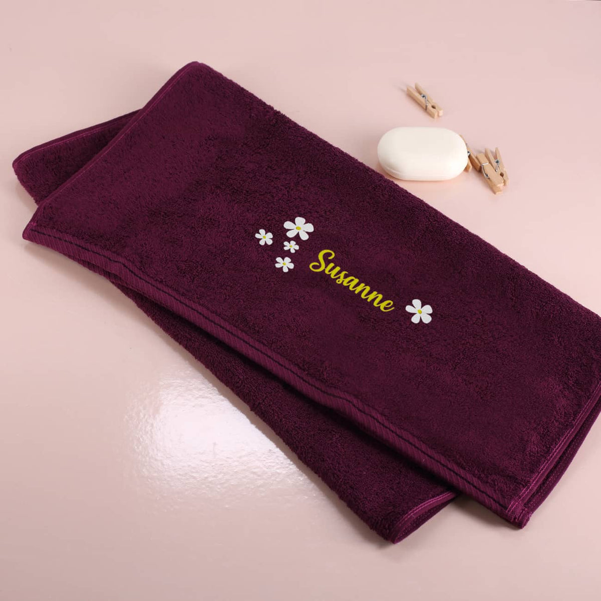 Brombeerfarbenes Badetuch mit Name und Blumen bestickt