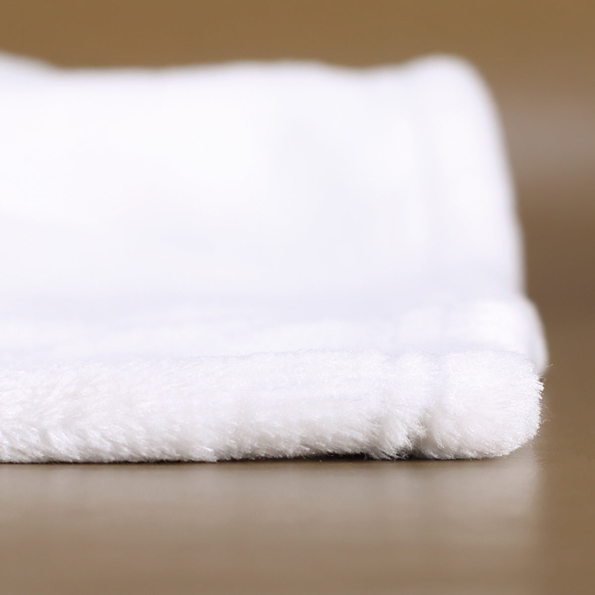 Seitenansicht der Kuscheldecke auf Tischfläche, dickes kuschelweiches Material und weiche Struktur im Detail sichtbar