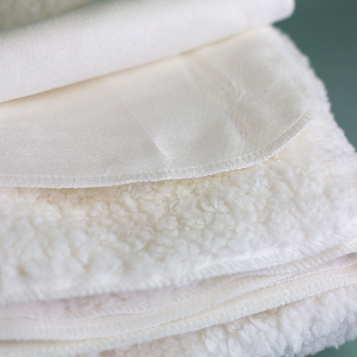 Detailaufnahme Kuscheldecke mit weicher Sherpa-Rückseite und flauschiger Struktur, Materialansicht der Decke