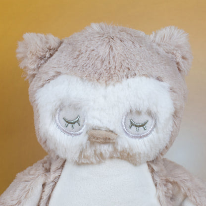 Nahaufnahme des Gesichts der Eule mit geschlossenen Augen, gestickten Wimpern und einem kleinen, beigen Schnabel. Das flauschige Fell ist in hellen Creme- und Beigetönen gehalten.