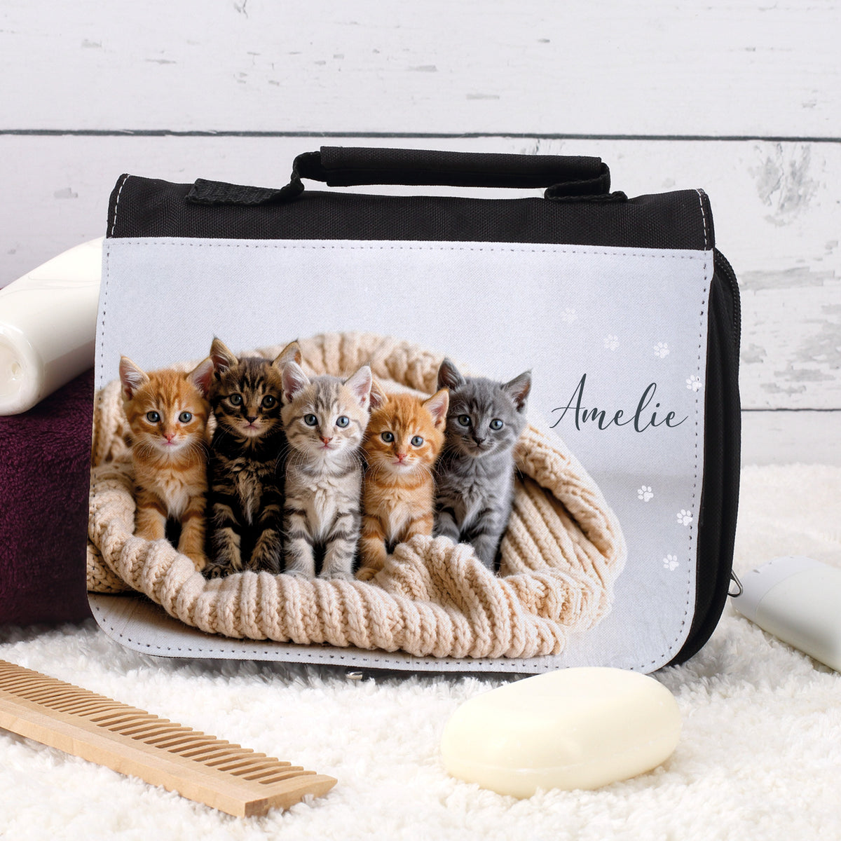 Kulturtasche mit Kätzchenmotiv und Name Amelie, liegend auf weißem Teppich mit Kamm und Seife