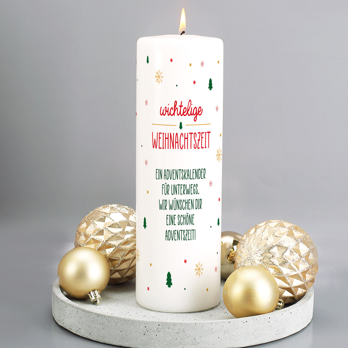 Brennende Adventskalender-Kerze mit Wichtelmotiv und personalisiertem Text, dekoriert mit goldenen Christbaumkugeln