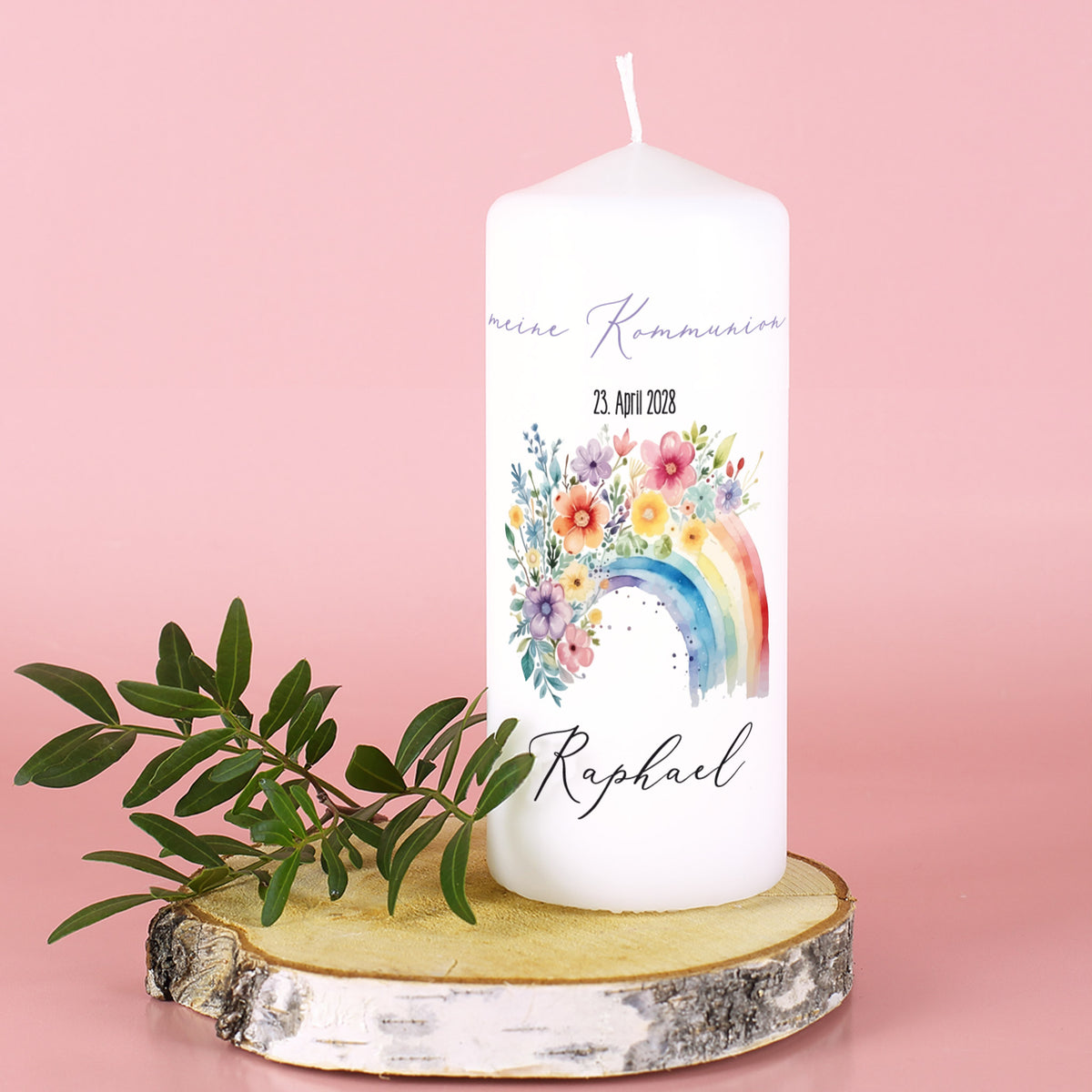Weiße Kerze mit Aufdruck „Meine Kommunion“, Datum und Name Raphael, vor rosa Hintergrund mit Holzplatte und Blättern